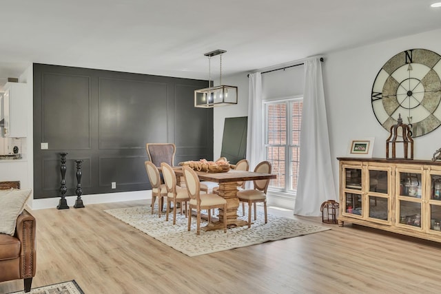 dining space with light wood-style floors and a decorative wall