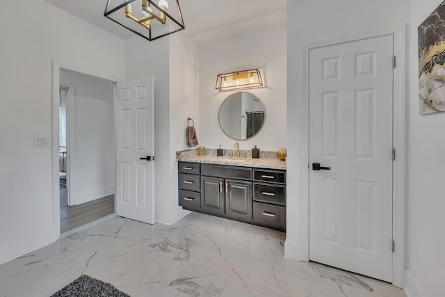 bathroom with marble finish floor, vanity, and baseboards