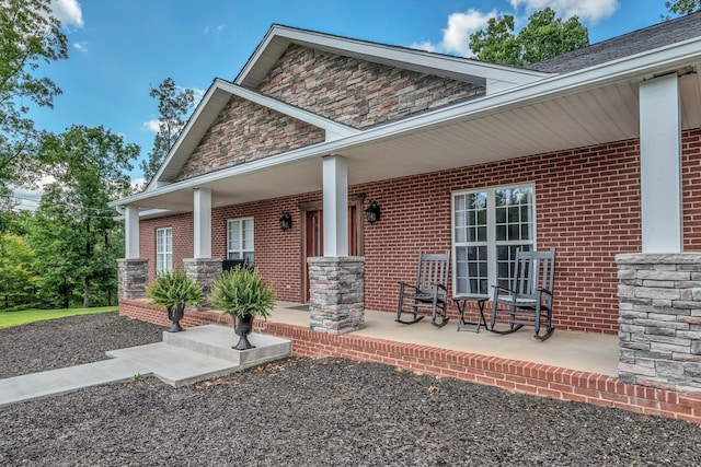 entrance to property with covered porch and brick siding