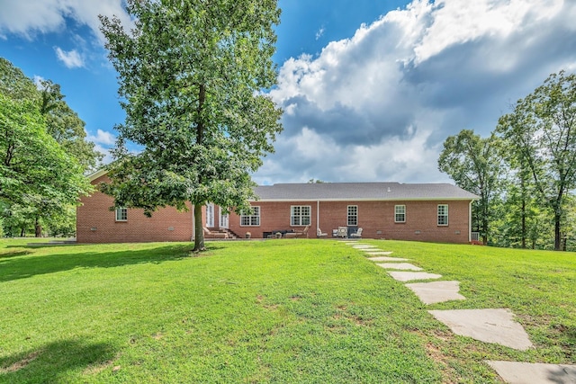 back of house with brick siding, crawl space, and a lawn