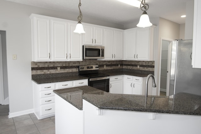 kitchen with light tile patterned floors, decorative backsplash, decorative light fixtures, stainless steel appliances, and white cabinetry