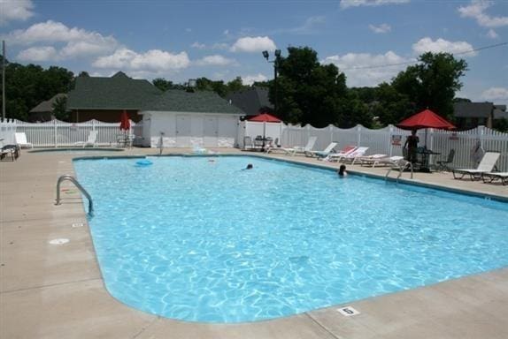 community pool with a patio and fence