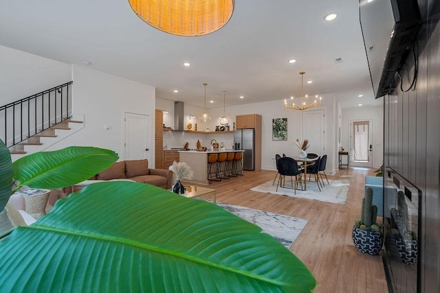 living area featuring an inviting chandelier, light wood-style flooring, stairs, and recessed lighting