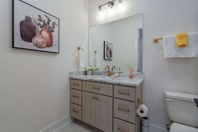 bathroom featuring toilet, marble finish floor, baseboards, and vanity