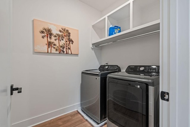 washroom featuring laundry area, baseboards, washing machine and clothes dryer, and wood finished floors