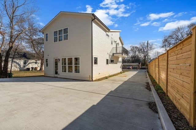 rear view of property featuring driveway and fence