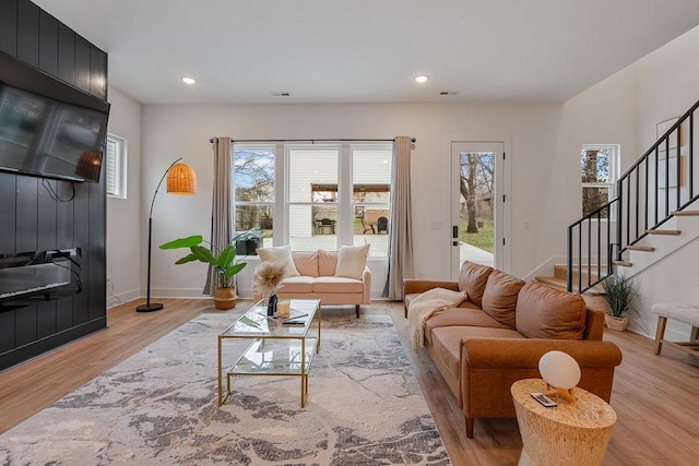 living area with recessed lighting, visible vents, baseboards, stairway, and light wood finished floors