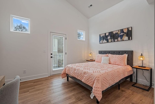 bedroom featuring access to exterior, visible vents, light wood-style floors, high vaulted ceiling, and baseboards