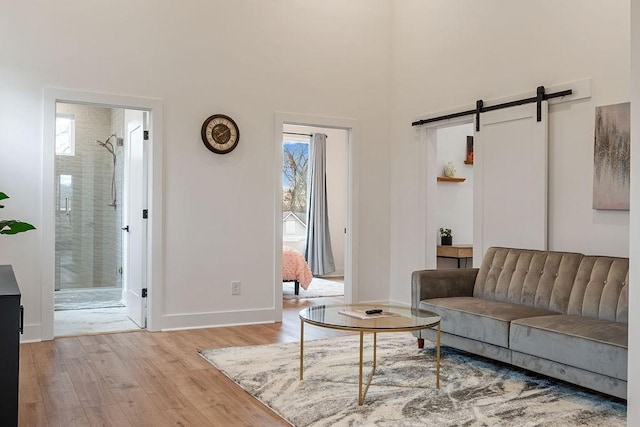 living area featuring light wood-style floors, a barn door, and baseboards