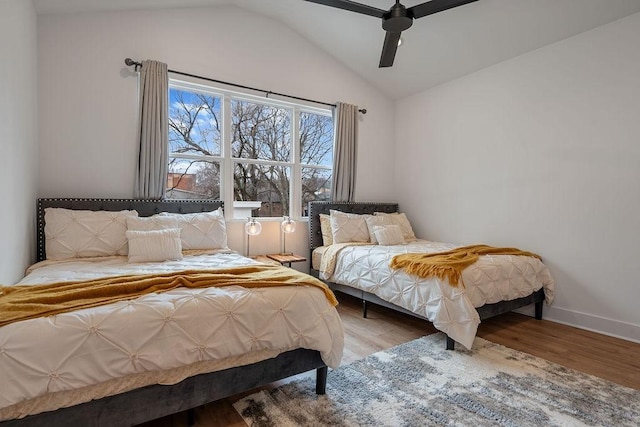 bedroom featuring a ceiling fan, lofted ceiling, baseboards, and wood finished floors