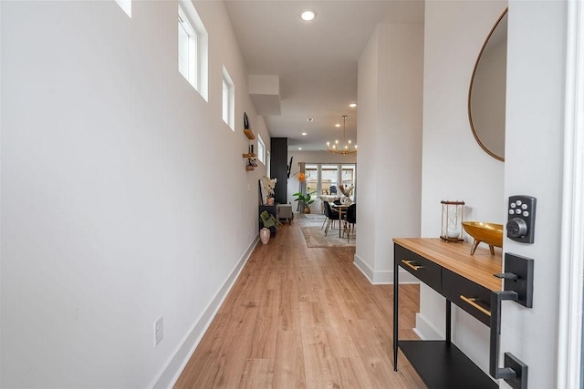 hall with a chandelier, recessed lighting, light wood-style flooring, and baseboards