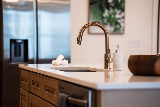 room details featuring light countertops, a sink, and dishwashing machine