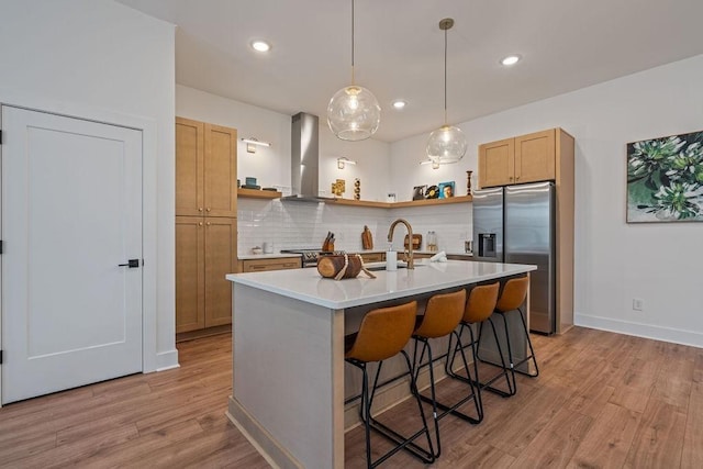 kitchen featuring a sink, light countertops, ventilation hood, stainless steel fridge with ice dispenser, and tasteful backsplash