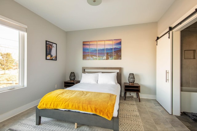 bedroom with a barn door and baseboards