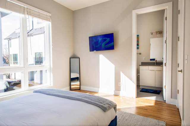 bedroom featuring a sink, wood finished floors, and baseboards