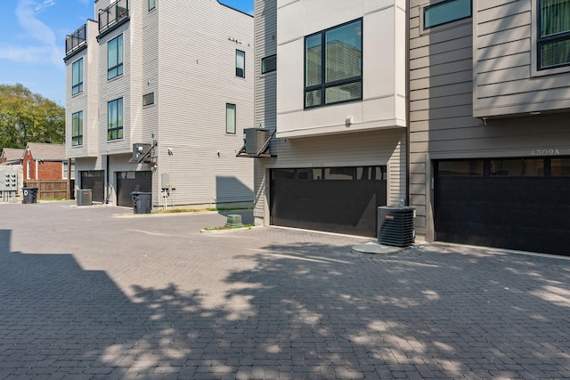 view of property exterior featuring central AC, driveway, and an attached garage