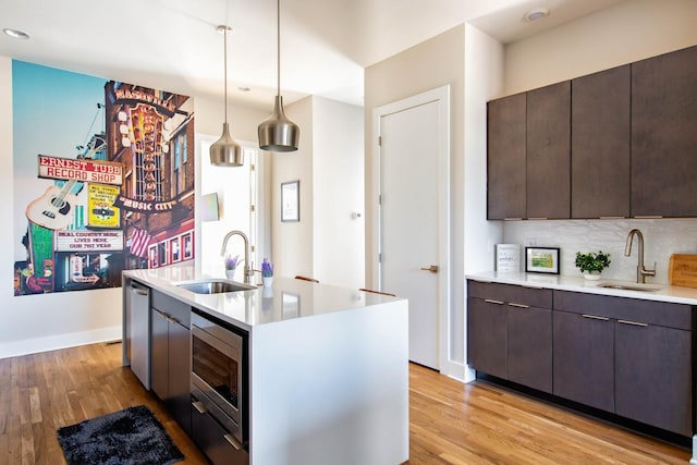 kitchen featuring light wood-type flooring, dark brown cabinetry, and a sink