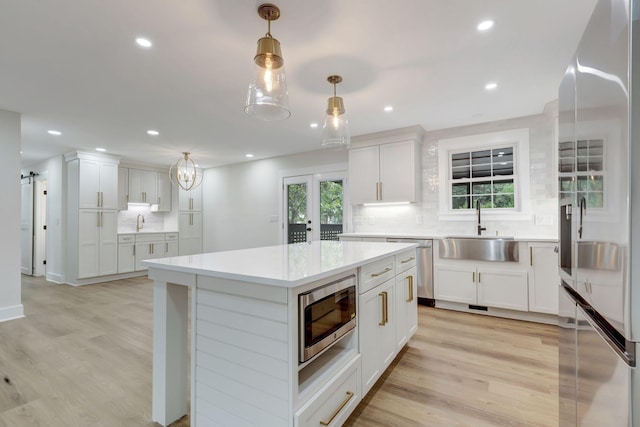 kitchen with light countertops, backsplash, a barn door, appliances with stainless steel finishes, and a sink