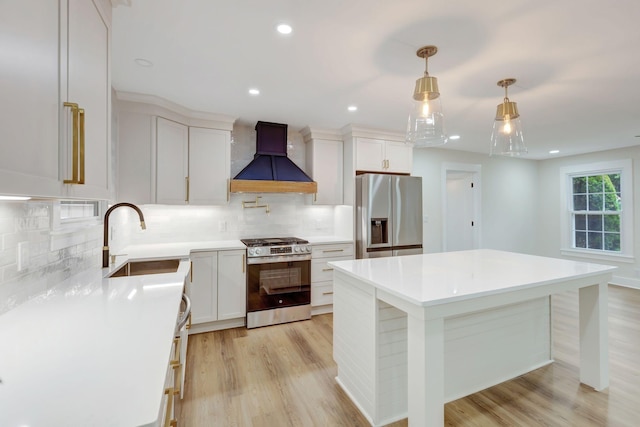 kitchen with light wood-style flooring, custom range hood, appliances with stainless steel finishes, light countertops, and a sink