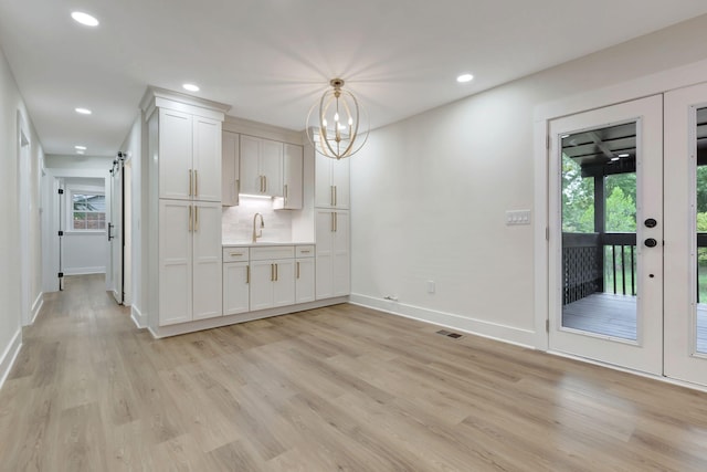 interior space with light wood finished floors, plenty of natural light, visible vents, and a barn door