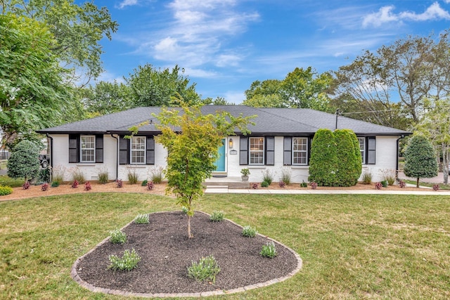 ranch-style house featuring a shingled roof, brick siding, and a front lawn