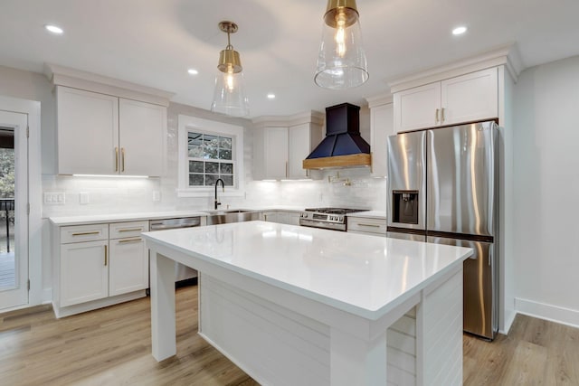 kitchen with appliances with stainless steel finishes, custom exhaust hood, light countertops, light wood-type flooring, and a sink