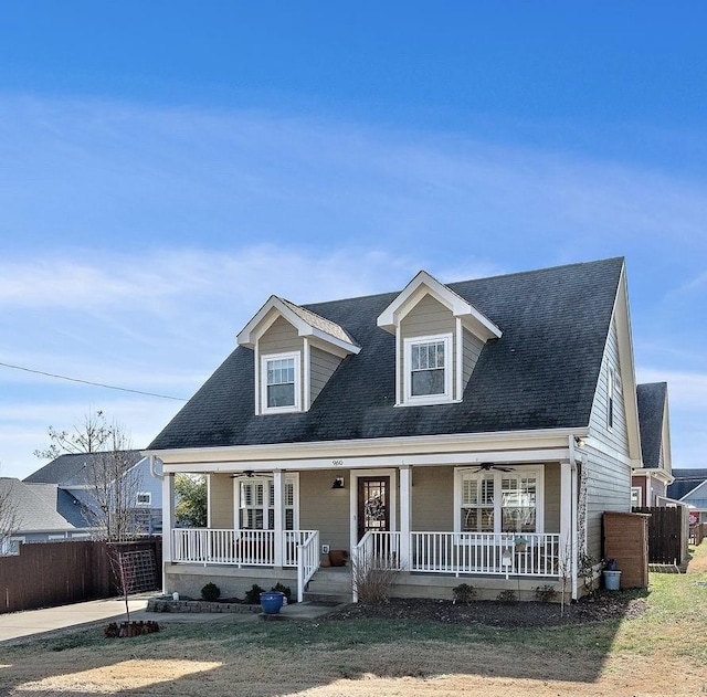 cape cod home with a porch, roof with shingles, fence, and ceiling fan