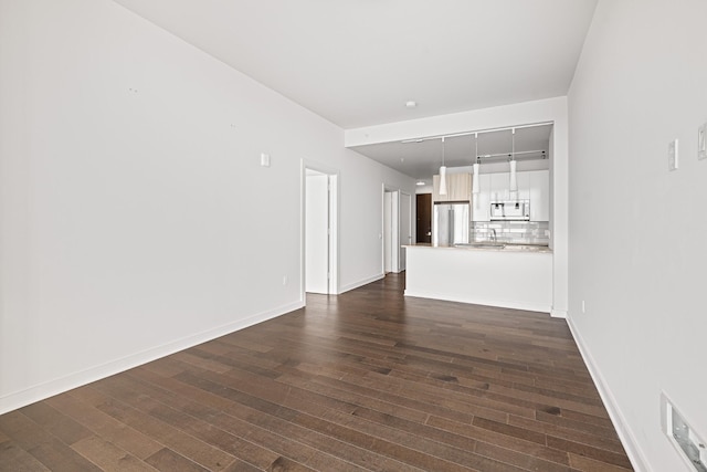 unfurnished living room with baseboards and dark wood-type flooring