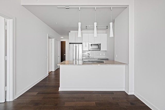 kitchen featuring white cabinetry, appliances with stainless steel finishes, tasteful backsplash, dark wood finished floors, and pendant lighting