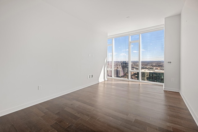 unfurnished room with baseboards, a wall of windows, and dark wood-style flooring