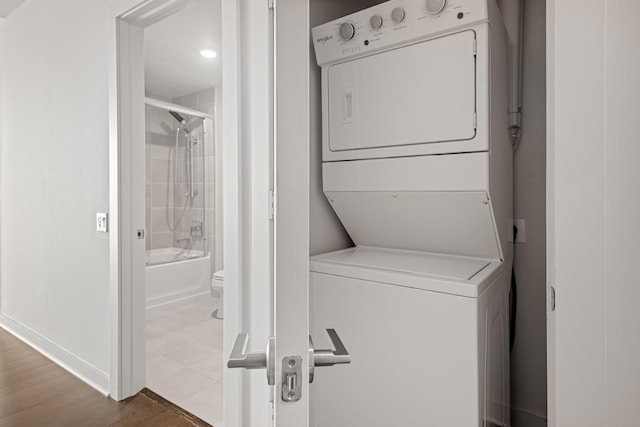 laundry area with laundry area, baseboards, and stacked washer / drying machine