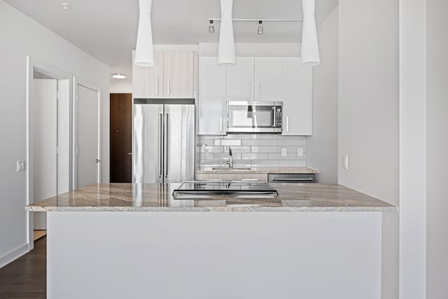 kitchen with dark wood-style flooring, a sink, white cabinets, appliances with stainless steel finishes, and tasteful backsplash