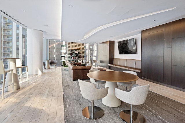 dining space with floor to ceiling windows, plenty of natural light, and light wood-style flooring