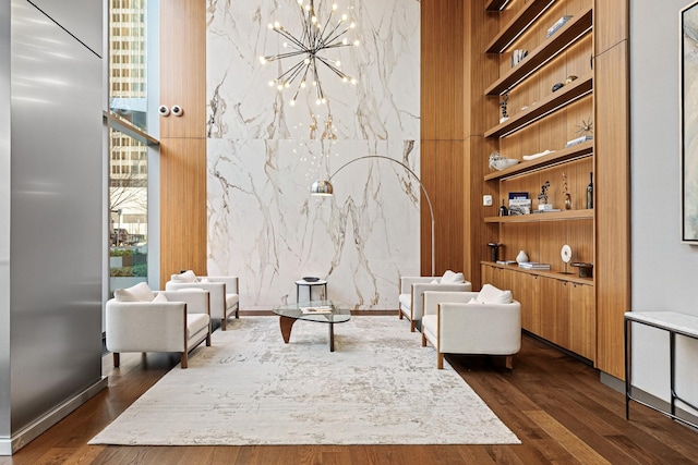 living area featuring built in shelves, dark wood-type flooring, and an inviting chandelier