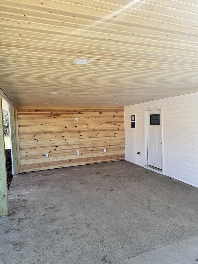 empty room featuring carpet floors, wooden ceiling, and wooden walls