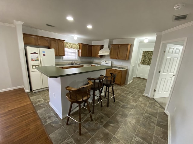 kitchen featuring white appliances, wall chimney exhaust hood, visible vents, and a sink