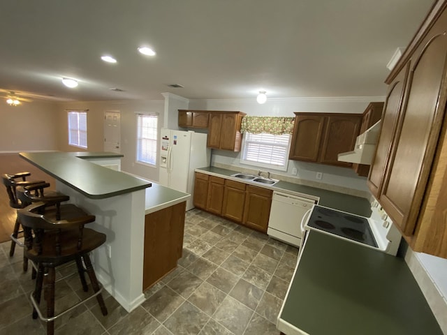 kitchen featuring a wealth of natural light, white appliances, a sink, and a breakfast bar area