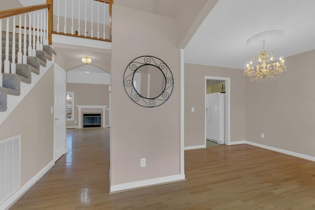 interior space featuring a chandelier, a fireplace, wood finished floors, visible vents, and baseboards