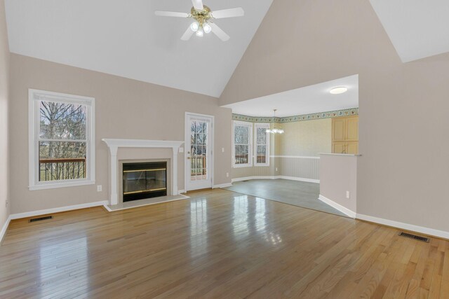 unfurnished living room featuring a healthy amount of sunlight, light wood-type flooring, visible vents, and a glass covered fireplace