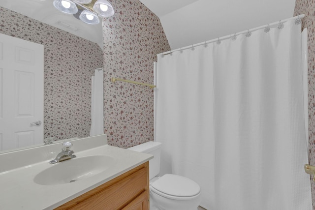 bathroom with vanity, toilet, and wallpapered walls