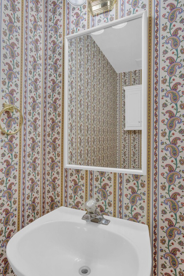 bathroom with wallpapered walls and a sink