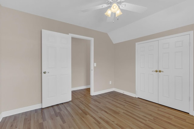 unfurnished bedroom with a closet, vaulted ceiling, light wood-style flooring, and baseboards