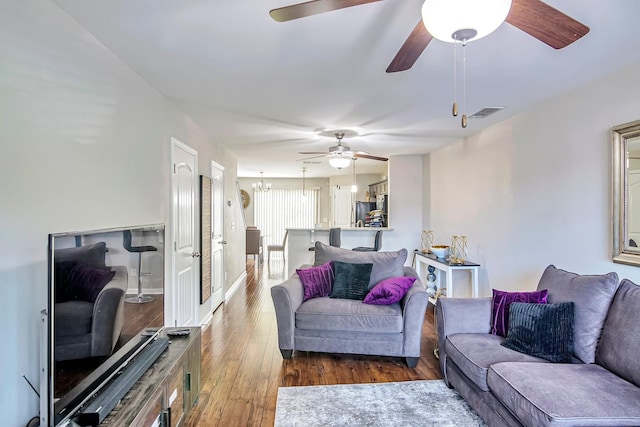 living area featuring visible vents, wood finished floors, and ceiling fan with notable chandelier