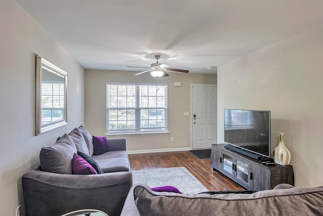 living room with baseboards, dark wood finished floors, and a ceiling fan