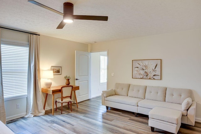 living area featuring baseboards, a textured ceiling, visible vents, and wood finished floors