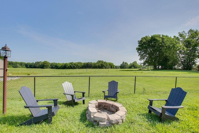 view of yard featuring a fire pit, a rural view, and fence