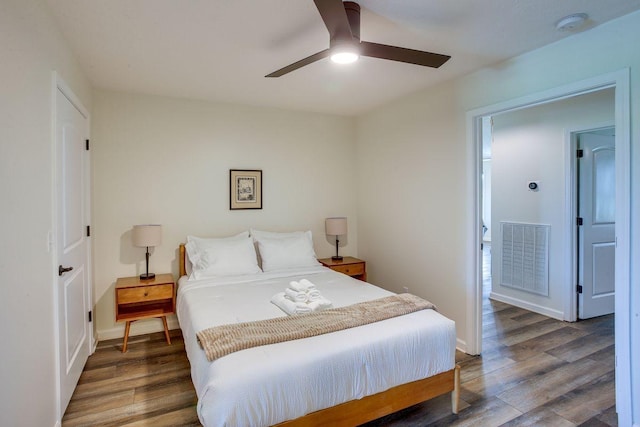 bedroom with a ceiling fan, baseboards, visible vents, and wood finished floors