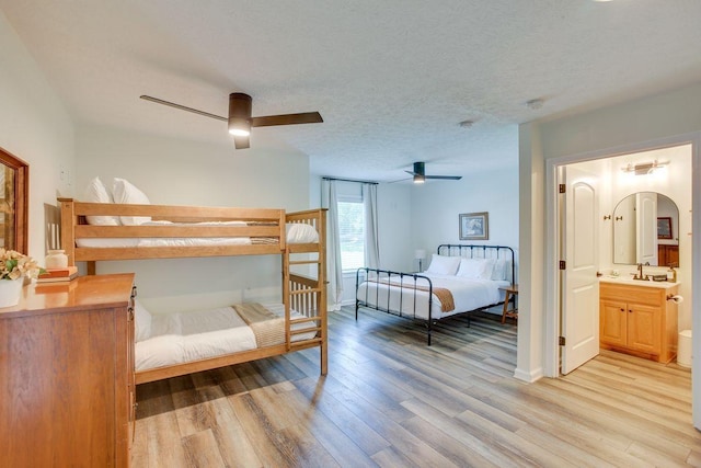 bedroom with light wood finished floors, arched walkways, connected bathroom, ceiling fan, and a textured ceiling