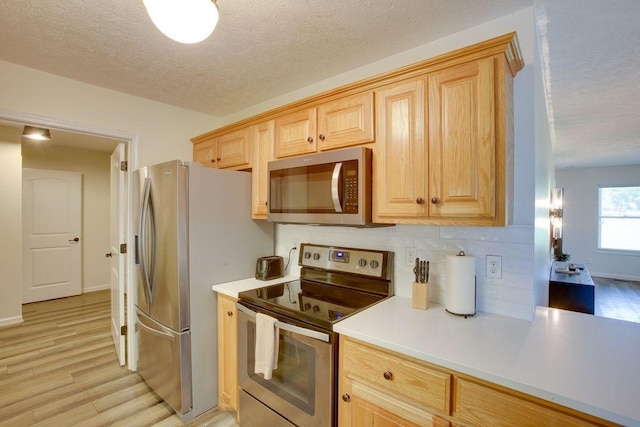 kitchen with tasteful backsplash, stainless steel appliances, light countertops, light wood-type flooring, and light brown cabinets