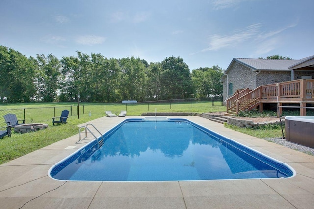 view of pool with an outdoor fire pit, a deck, a lawn, and a fenced backyard